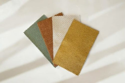 four different coloured fabric swatches on a white floor